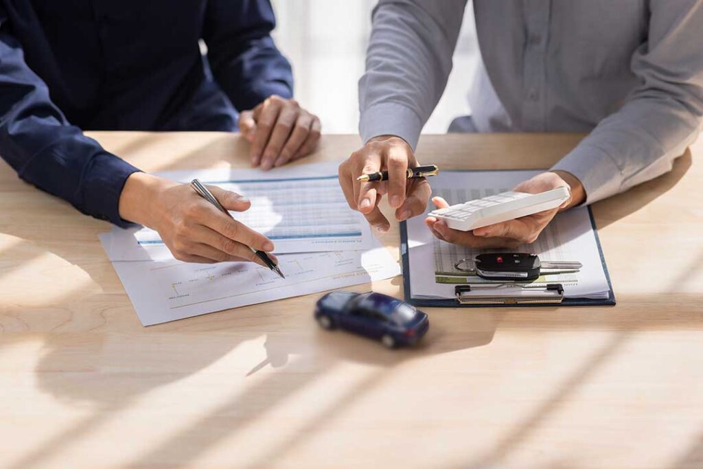 Homeowner reviewing insurance papers at a kitchen table beside a roof inspection report and safety checklist