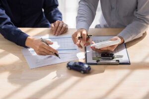 Homeowner reviewing insurance papers at a kitchen table beside a roof inspection report and safety checklist
